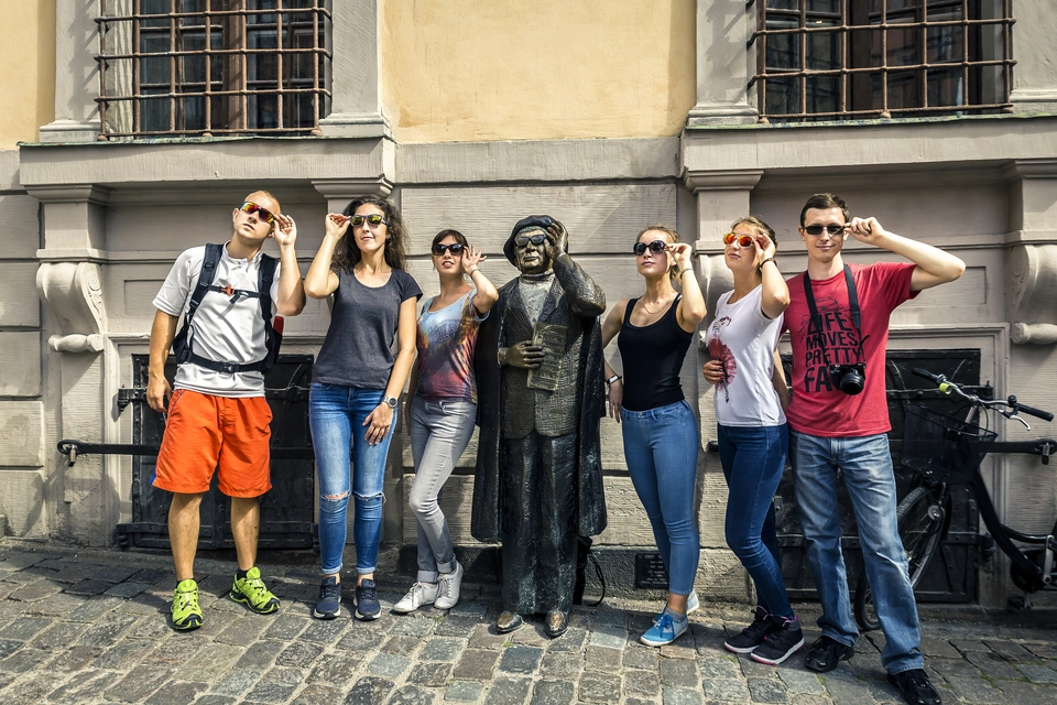 A group of people is imitating a statue of a man holding his glasses at Järntorget.